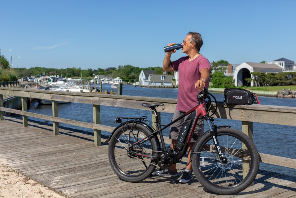 Man drinking water while holding his e-bike